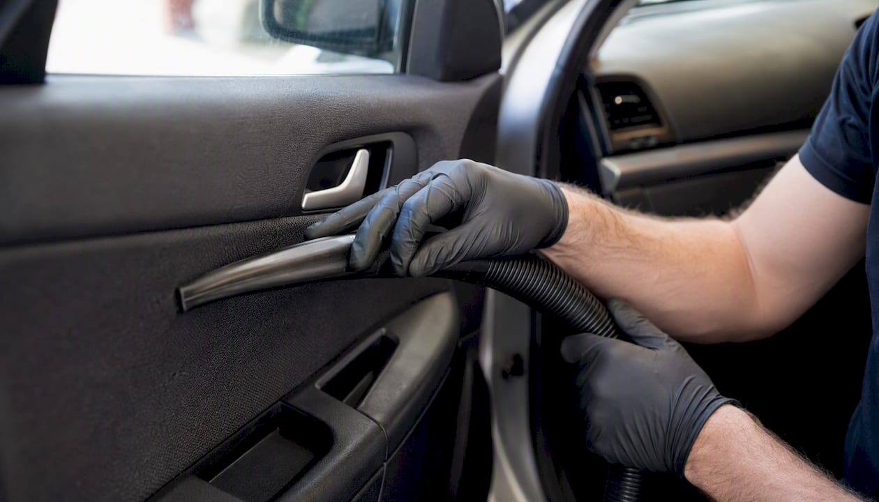 Hands vacuuming car headliner interior