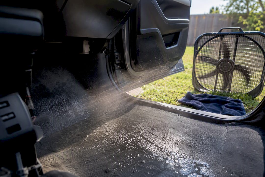 Box fan blowing air onto wet car carpet