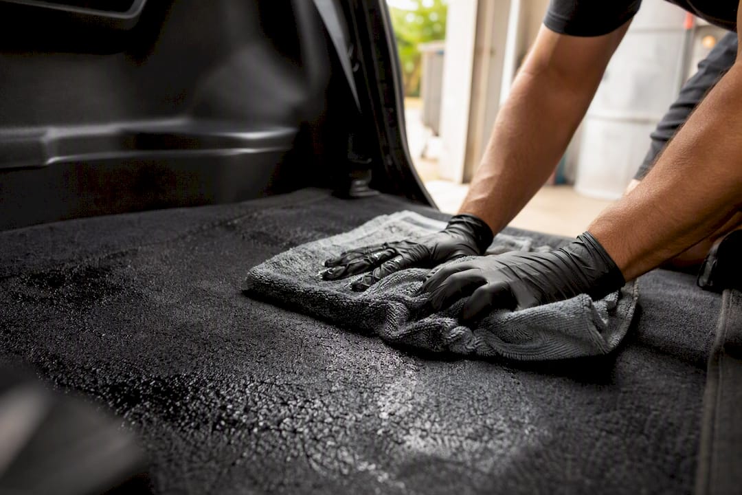 Hands pressing microfiber towel on wet carpet
