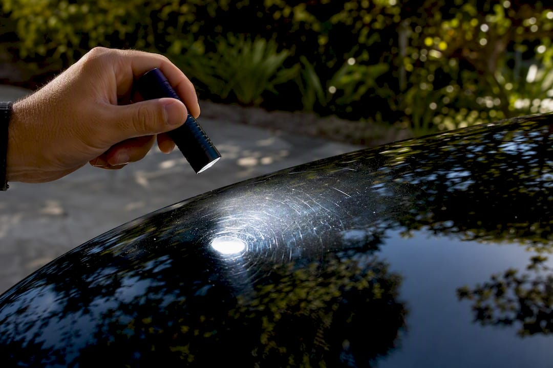 Detailer inspecting paint with swirl finder light
