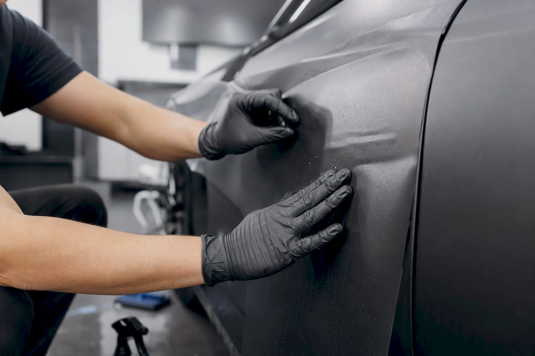 Hands applying matte paint protection film close-up