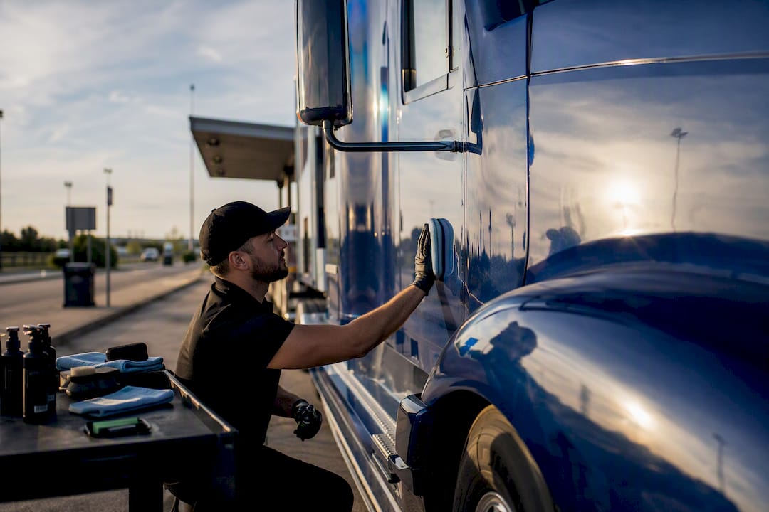 Technician spraying cleaning solution on semi truck cab