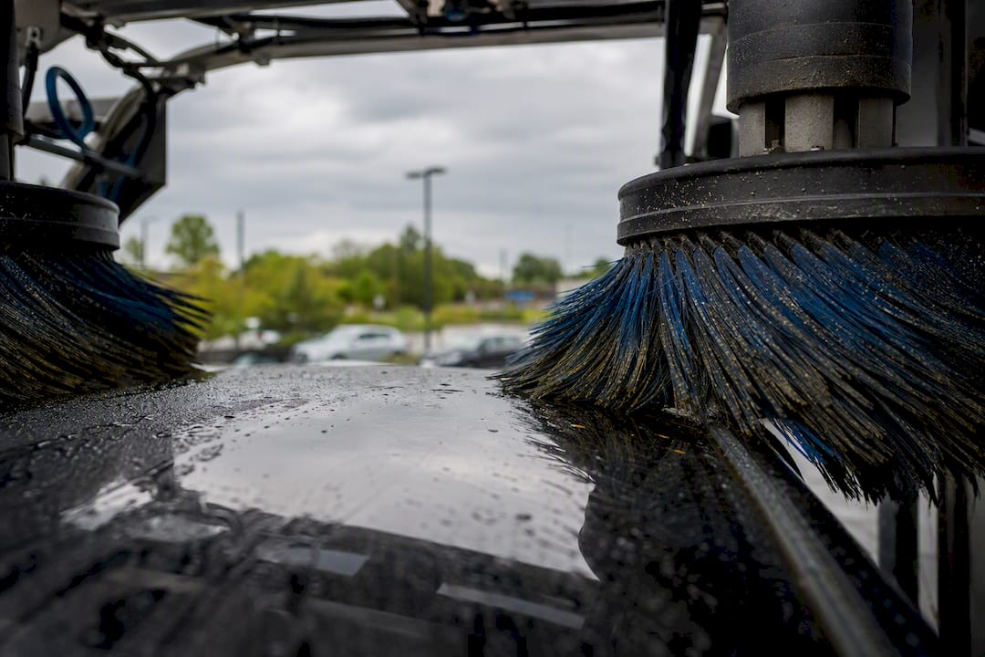 Spinning car wash brushes near car paint