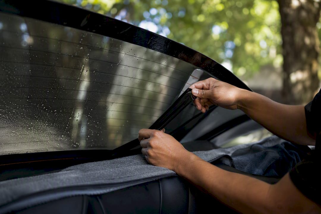 Hands peeling rear window tint film carefully