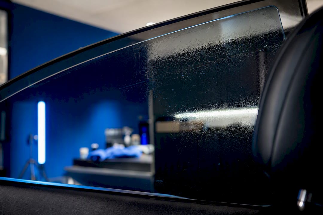 Fresh window tint curing inside a detailing bay