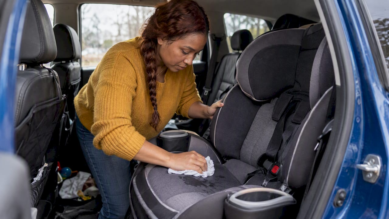 Parent gently wipes a child car seat cover